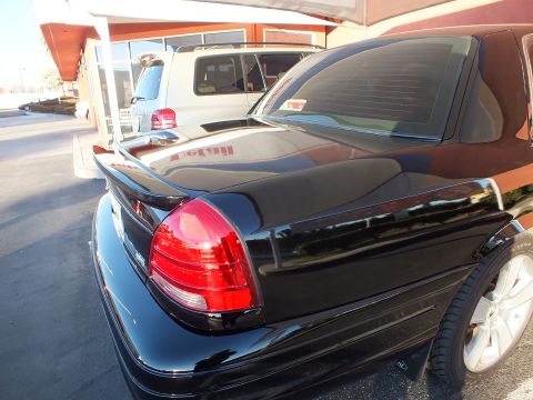 2003 Ford Crown Victoria - Close rear view of a black sedan's decklid spoiler and vertical tail lamp.