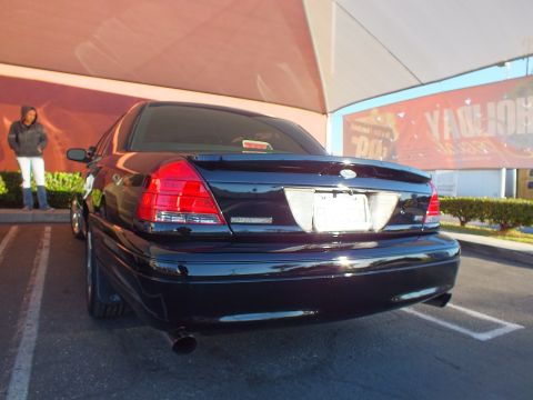 2003 Ford Crown Victoria - Rear of a black Ford Crown Victoria, Police Interceptor badging visible, parked beside a striped lot.