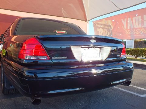 2003 Ford Crown Victoria - Tail of a glossy black Crown Victoria; Police Interceptor lettering and clear taillight lenses shown.