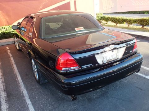 2003 Ford Crown Victoria - Rear quarter of a black Crown Victoria; EVIL VIC plate and Police Interceptor badge visible.