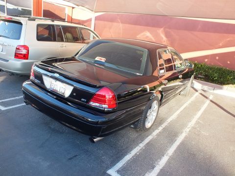 2003 Ford Crown Victoria - Right rear of a black Crown Victoria sedan in a striped lot next to a silver minivan.