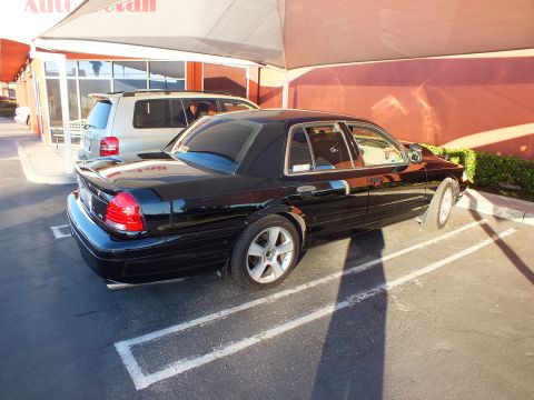 2003 Ford Crown Victoria - Side-rear view of a black Crown Victoria on alloy wheels parked at an auto detail shop.