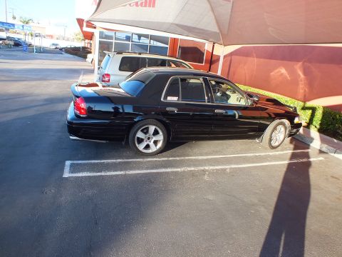 2003 Ford Crown Victoria - Full right profile of a lowered black Crown Victoria sedan parked outside an auto shop.