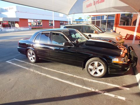 2003 Ford Crown Victoria - Left profile of a black Crown Victoria sedan parked diagonally in front of Auto Detail shop.