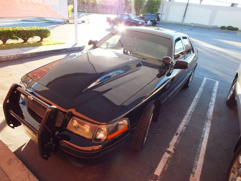 2003 Ford Crown Victoria - High-angle front-left of a black Crown Victoria with grille guard and chrome mirrors.