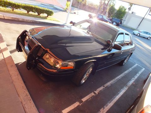 2003 Ford Crown Victoria - Top-down front-left of a black Crown Victoria with push bar, sun reflecting off the roof.