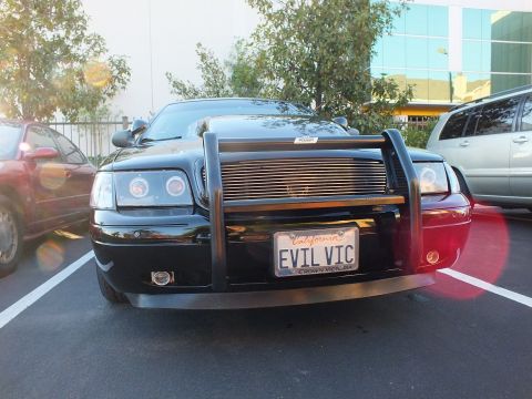 2003 Ford Crown Victoria - Head-on front of a black Crown Victoria with brush guard, projector halos and EVIL VIC plate.