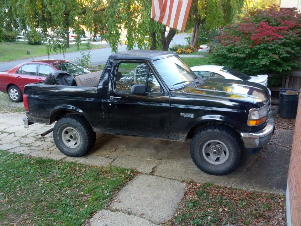 Black Ford Bronco with a removable top parked on a cracked concrete driveway