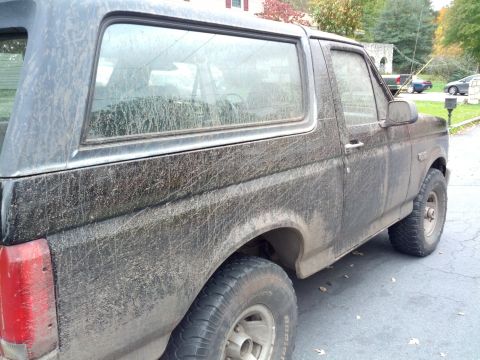 1995 Ford Bronco - This heavily soiled Ford Bronco is viewed from the side, revealing its weathered exterior.
