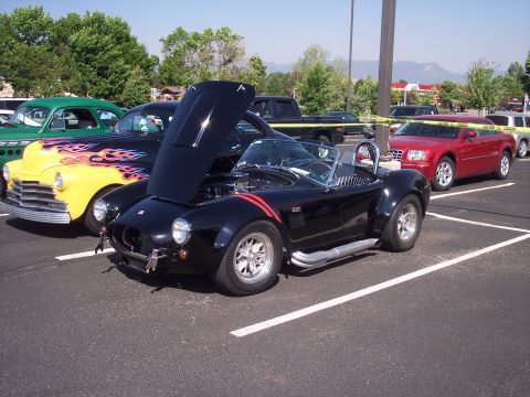1972 Ford Ranchero - Several cars are parked in a lot, including a black convertible with its hood up.