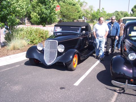 1972 Ford Ranchero - A black convertible with orange wheels is parked next to another vehicle.