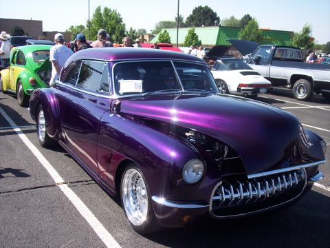 1972 Ford Ranchero - A highly customized purple coupe with an elaborate chrome grille is displayed at a car show.