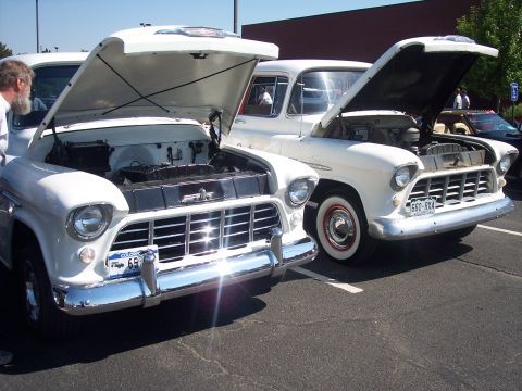 1972 Ford Ranchero - Two classic white pickup trucks are parked side-by-side with their hoods raised, revealing their engines.