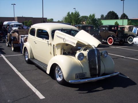 1972 Ford Ranchero - A cream-colored sedan from the 1930s is displayed with its hood open, revealing the engine, at an outdoor car show.
