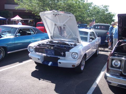 1972 Ford Ranchero - White 1965 Ford Mustang coupe with hood open at a car show.