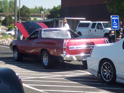 1972 Ford Ranchero - A red 1972 Ford Ranchero is parked with its hood open, alongside other vehicles in a parking lot.