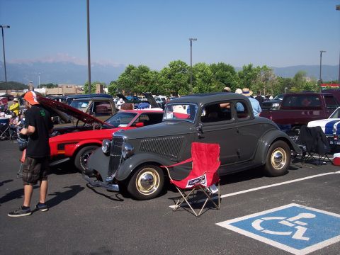 1972 Ford Ranchero - A dark gray coupe is parked in a lot, with a red chair placed in front of it.