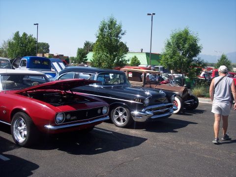 1972 Ford Ranchero - Several classic cars are parked in a lot on a sunny day, with a man walking away from the camera.