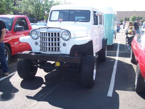 1972 Ford Ranchero - A white panel van with a prominent grille and custom bumper is parked at an outdoor event.
