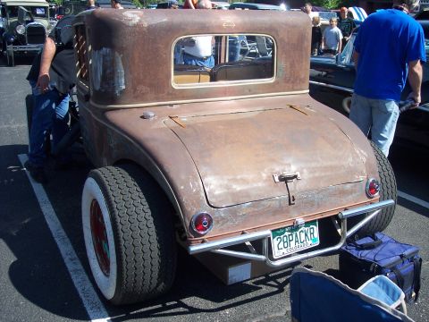 1972 Ford Ranchero - A weathered hot rod coupe is parked at an outdoor event, its rear end prominently displayed.