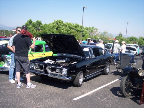 1972 Ford Ranchero - A black 1967 Plymouth Barracuda is displayed with its hood open at an outdoor car show.
