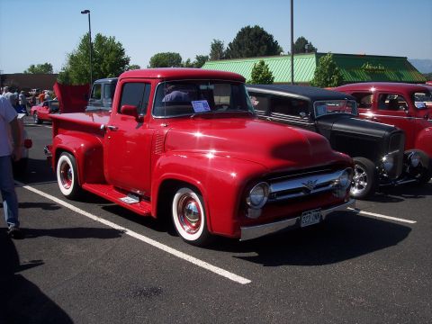 1972 Ford Ranchero - A bright red 1956 Ford F-100 pickup truck is parked at a car show.