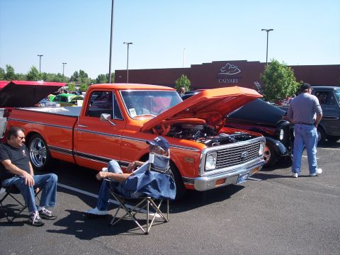 1972 Ford Ranchero - A bright orange 1971 Chevrolet C10 pickup truck is displayed with its hood open at a car show.