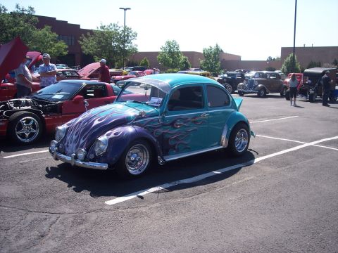 1972 Ford Ranchero - A customized Volkswagen Beetle with flame graphics is displayed at an outdoor car event.