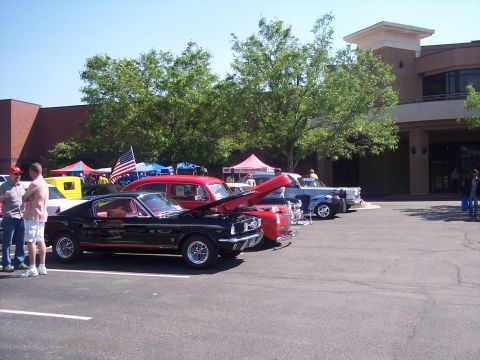 1972 Ford Ranchero - Several classic cars are lined up in a parking lot, including a black 1965 Ford Mustang.