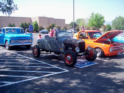 1972 Ford Ranchero - Three vehicles are parked in a lot, including a hot rod and two pickup trucks. The orange truck has its hood open.
