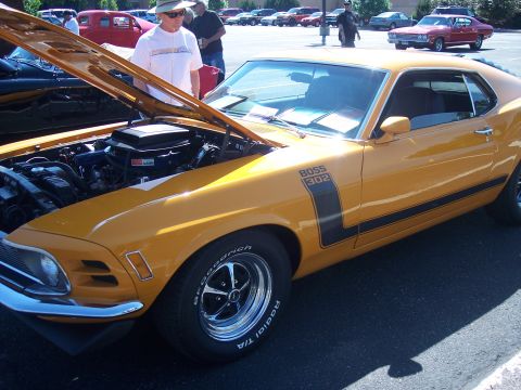 1972 Ford Ranchero - A yellow 1970 Ford Mustang Boss 302 is displayed with its hood open, parked outdoors among other vehicles.