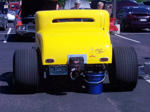 1972 Ford Ranchero - A bright yellow hot rod is parked outdoors, showing its rear end and oversized tires.