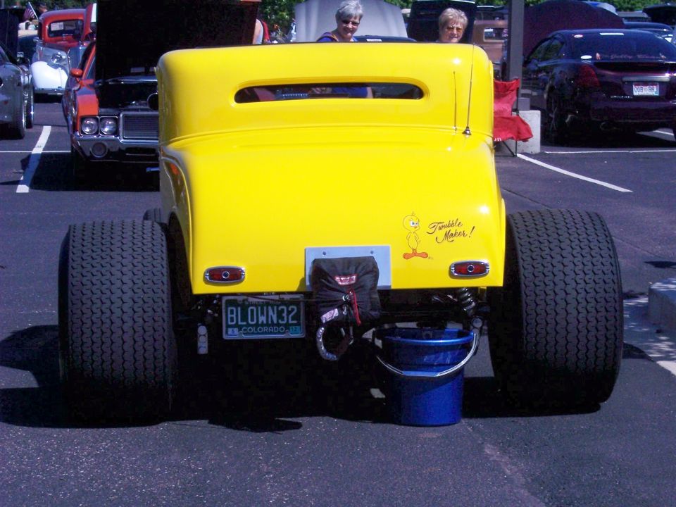 Yellow hot rod with large rear tires, custom license plate 'BLOWN32', and Tweety Bird sticker