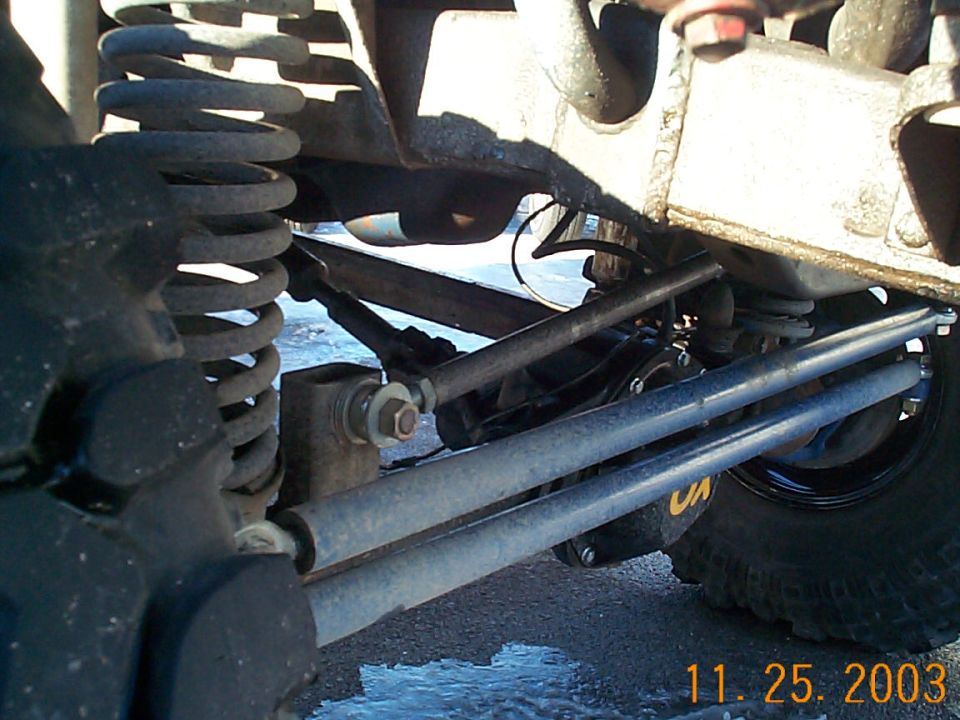 Underside view of a lifted 4x4 front axle steering linkage, coil spring and radius arm