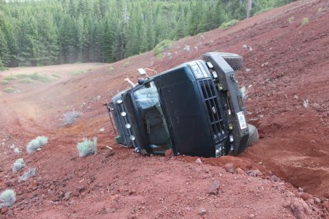1995 Ford Bronco - A black 1995 Ford Bronco has rolled onto its side on a steep, red dirt embankment.