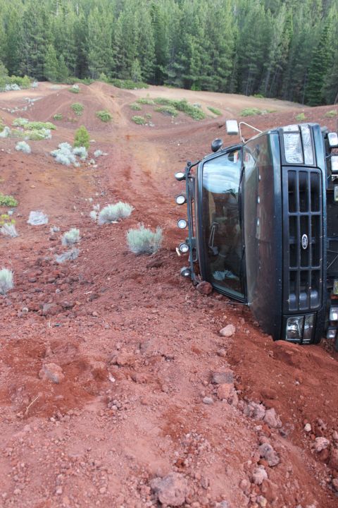 1995 Ford Bronco - A truck has rolled onto its side in a , off-road environment.