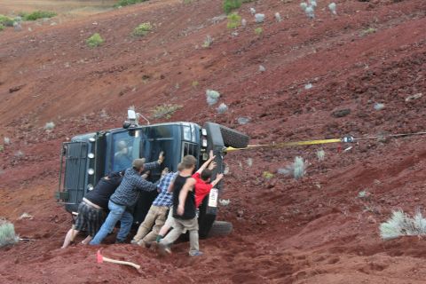 1995 Ford Bronco - Off-road recovery: a group attempts to right a tipped-over SUV on a rocky, red dirt incline.