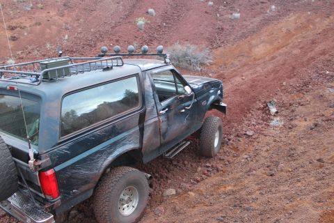 1995 Ford Bronco - Ford Bronco navigates a steep, rocky incline in a desert landscape.