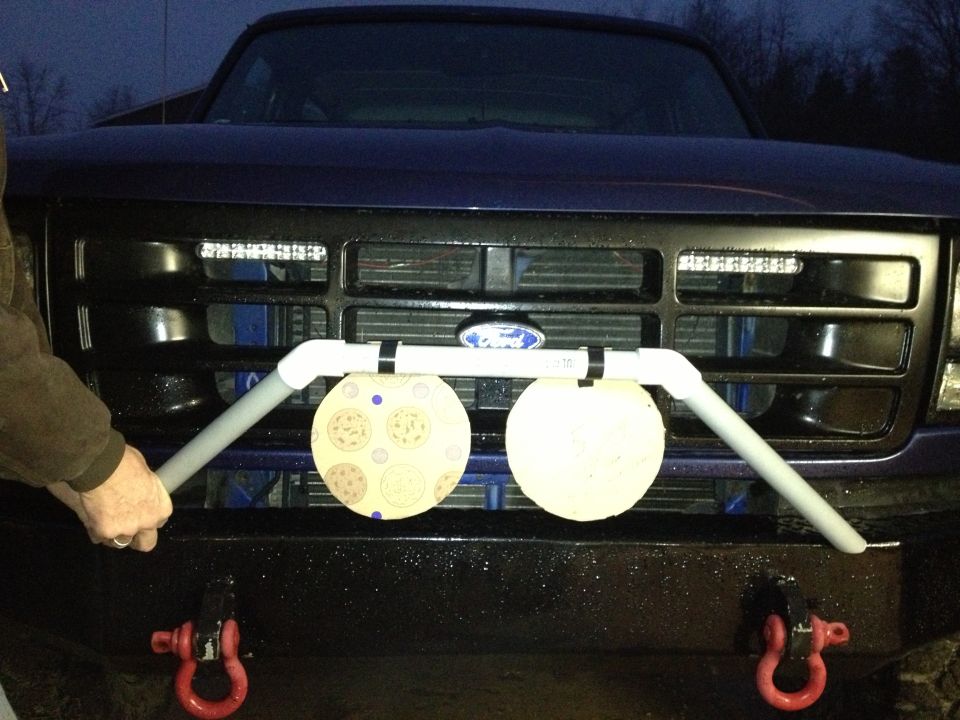 Dark blue Ford truck grille with a custom PVC pipe mount holding two circular targets