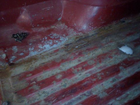 1978 Ford Bronco - Interior view of a red vehicle floor showing signs of rust and a cluster of bolts.