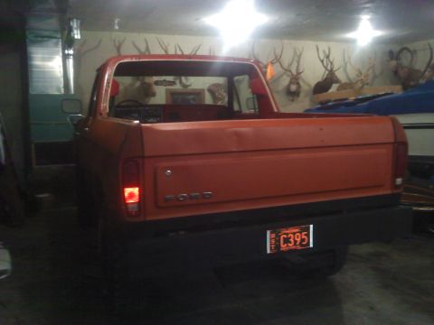 1978 Ford Bronco - Rear view of an orange pickup truck with a black bumper and a license plate.