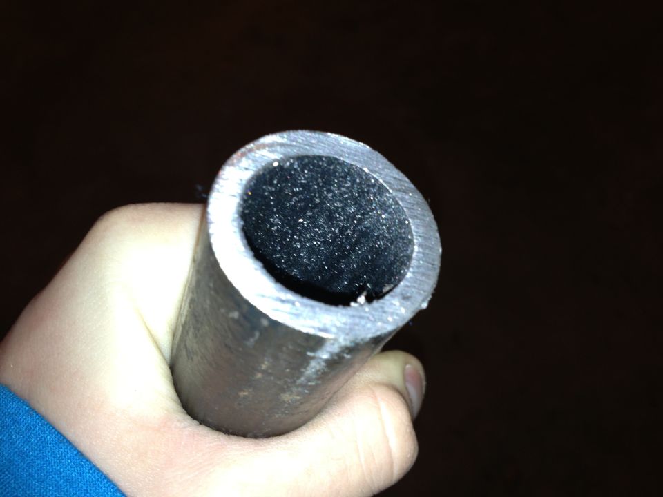 Close-up of a hand holding a cut metal pipe with a dark interior