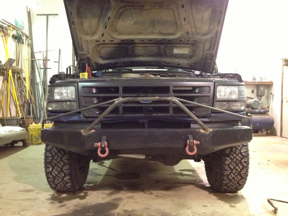 Front view of dark blue SUV with aftermarket bumper and hood open