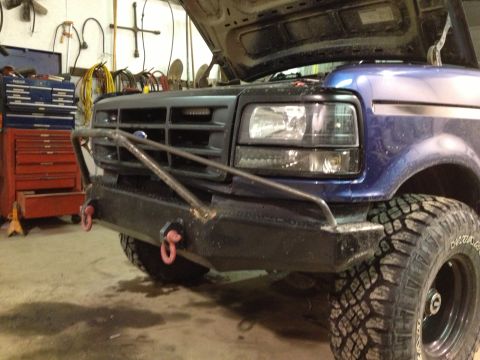 1996 Ford Bronco - Front view of a blue Ford truck with its hood open, parked in a garage with tools.
