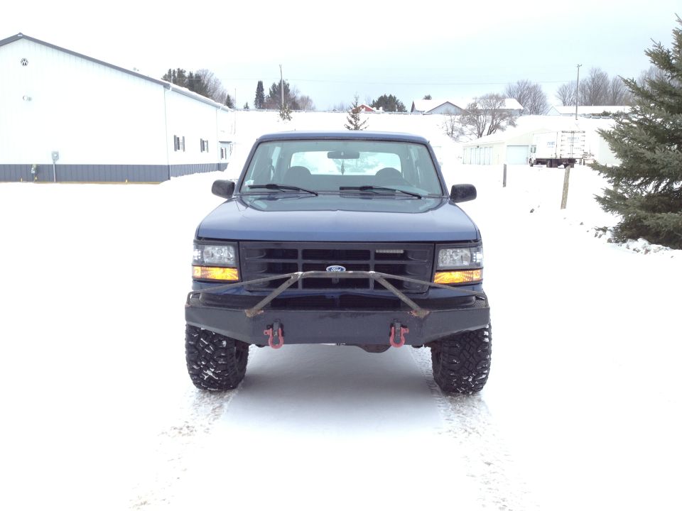 Blue 1996 Ford Bronco front view with aftermarket bumper and tires in snow