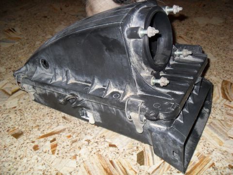 1990 Ford Bronco - A black plastic mass air sensor housing is shown from a side angle on a tiled surface.