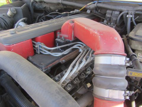 1997 Dodge 3500 - Detail of a diesel engine's red intake pipe and fuel injectors, showing wear and dust.