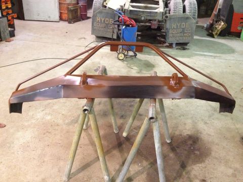 1996 Ford Bronco - A custom brown front bumper is mounted on sawhorses in a workshop, with a truck in the background.