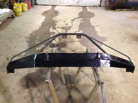 1996 Ford Bronco - A black aftermarket bumper with a brush guard is shown mounted on sawhorses in a garage.