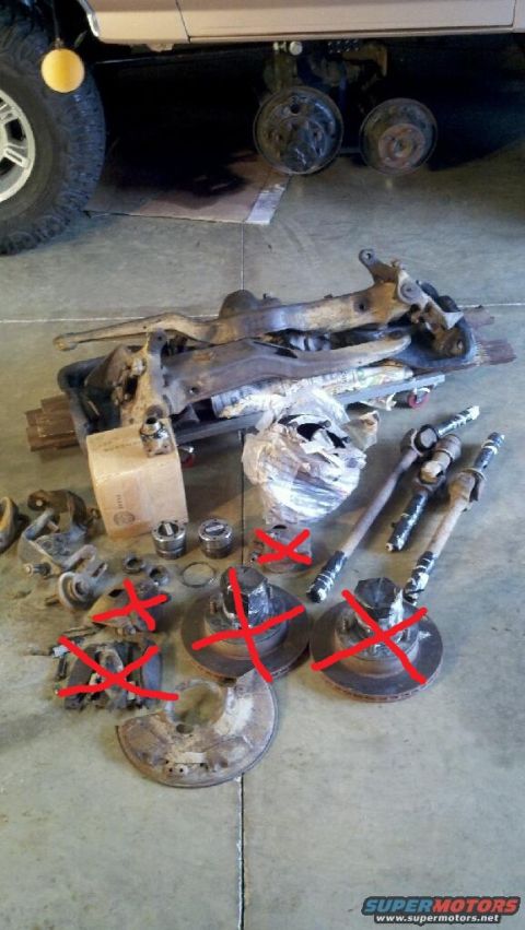 1995 Ford Bronco - Assorted vehicle suspension and brake parts laid out on a concrete floor.